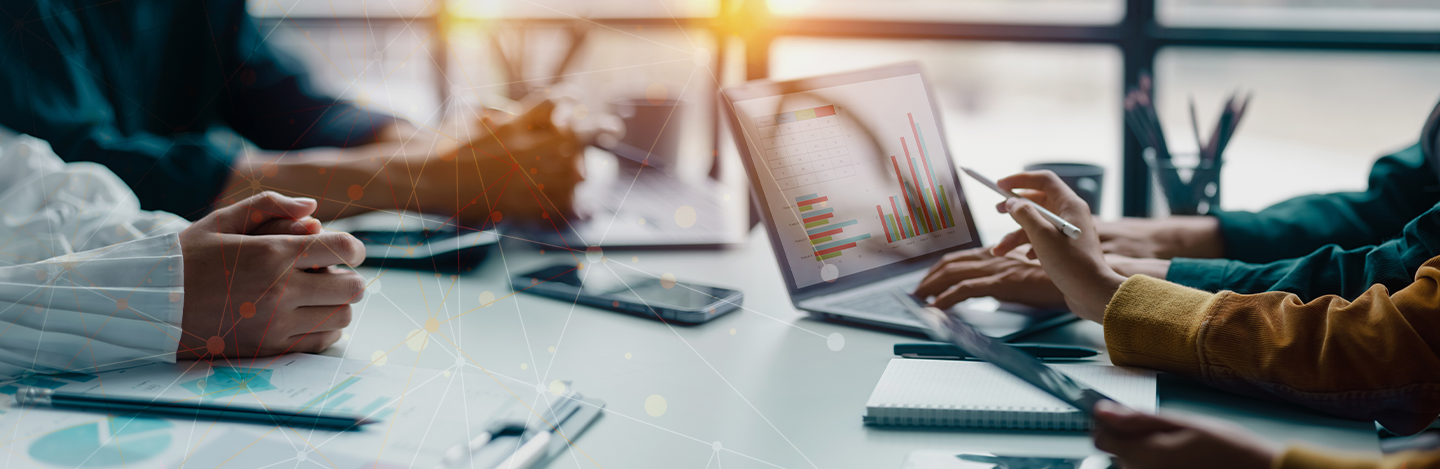 People working together at a table with a laptop and some notepads to take notes.